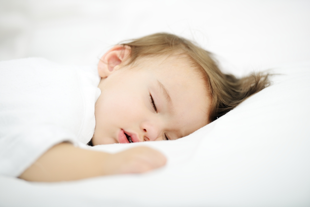 Adorable baby sleeping on white bed with copy space